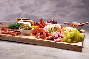 Cutting board with prosciutto, salami, cheese,bread and olives on dark stone background