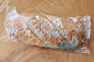 Moldy bread on a wooden background. Improper storage of food.