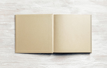 Book or brochure with blank craft paper pages on light wooden background. Mockup for placing your...