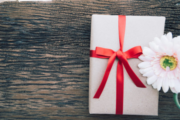 box with red ribbon and bow on wooden background