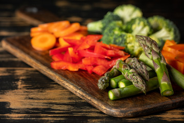 Raw vegetables cooking - carrot, paper, asparagus, broccoli and greens on wooden table background.