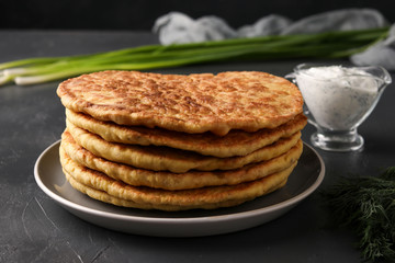 Homemade tortillas, located on a plate on a dark background, pictured green onions and sour cream