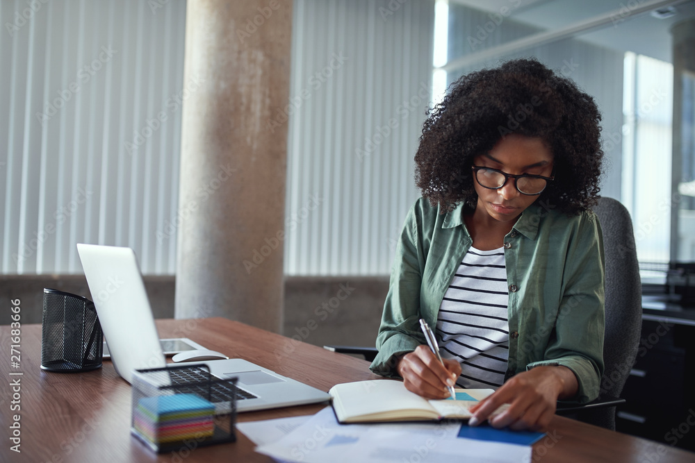 Wall mural Businesswoman writing in an agenda on a desk at office