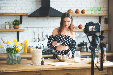 Pretty young woman girl food blogger in polka dot dress working on a new video and explaining how...