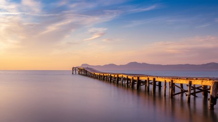 Wooden pier / jetty, playa de muro, Alcudia, sunrise, mountains, secluded beach, golden sunlight, reflection, beautiful sky, clouds,landmark, mallorca, spain.