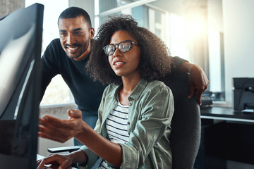 Businesswoman showing something to her colleague on computer