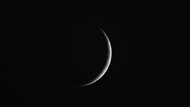 Close up of waxing crescent Moon with craters details, with dark background.
