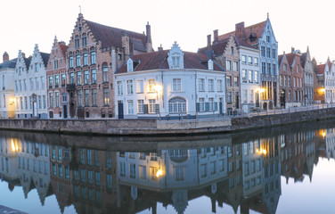 Naklejka premium Scenic city view of Bruges canal with beautiful medieval colored houses and reflections in the evening.