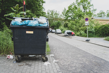 Overflowing yellow garbage container jammed up with waste