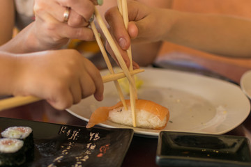 Fototapeta premium A hand with chopsticks takes sushi.