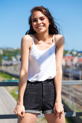Obraz premium Smiling brunette model in white summer blouse, summer street outdoors