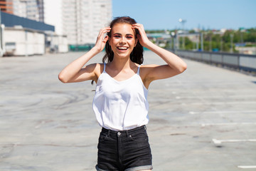 Fototapeta premium Pretty young brunette model in white summer blouse and jeans, summer street outdoors