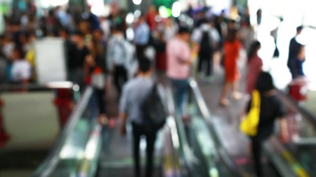 Many people are walking down with escalators at skytrain station. Blurry of people getting on and out electric skytrain, railroad transportation for passenger in city, traveler and urban lifestyle.