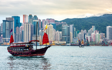 Fototapeta na wymiar Chinese traditional junk boat in front of Hong Kong skyline