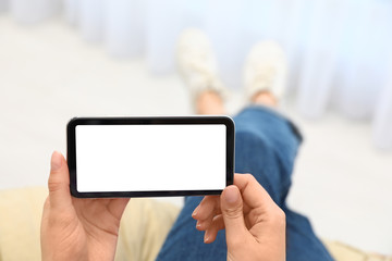 Woman holding smartphone with blank screen indoors, closeup of hands. Space for text