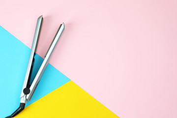 Modern hair iron for straightening on color background, top view with space for text