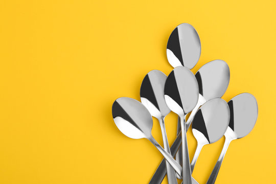 Flat lay composition with clean tablespoons and space for text on color background