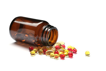 Bottle with different vitamin capsules on white background