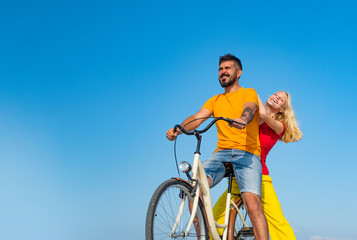 Young riders enjoying themselves on trip. Stylish and loving couple enjoying. Couple in love riding a bike. Attractive couple on a bike ride on a sunny day. Couple with vintage bike.