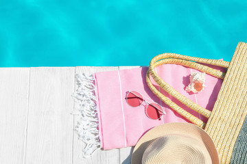 Flat lay composition with beach accessories on wooden deck near swimming pool. Space for text