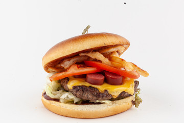 Close-up of a beef burger stuffed with crispy onion rings, chop, salad and chorizo isolated