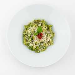 Italian pasta with pesto, basil and parmesan on a white studio background