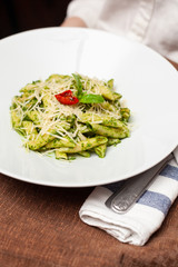 Waiter is holding a tray with bright green pesto pasta