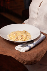 Waiter is serving creamy italian carbonara with bacon and parmesan
