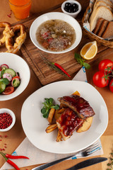 Close up of bbq fried ribs in a spicy sauce with baked potato, served in a white dish and as a part of nutritious set meal in a restaurant