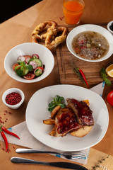 Close up of bbq fried ribs in a spicy sauce with baked potato, served in a white dish and as a part of nutritious set meal in a restaurant