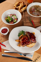 Close up of bbq fried ribs in a spicy sauce with baked potato, served in a white dish and as a part of nutritious set meal in a restaurant