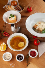 Mouthwatering three course meal deal: hot piece of italian lasagna, risotto and cabbage soup with egg, served on a wooden table, decorated with yummy ingredients