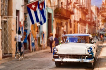  Cubaanse vlaggen, oude auto en rottende gebouwen in Havana © kmiragaya
