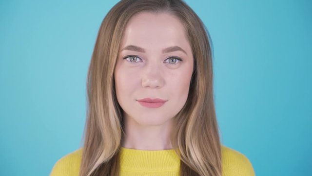 Close-up portrait. Calm girl on a blue background. Isolated background. 4 K