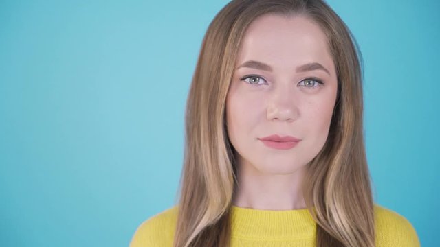 Close-up portrait. girl on a blue background. cute girl gently smiles and shy. Isolated background. Place for inscription left. 4k