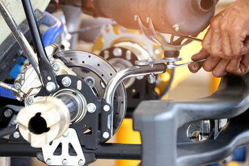 Worker hand tightening or loosening a nut of a bolt with a wrench for automotives part.