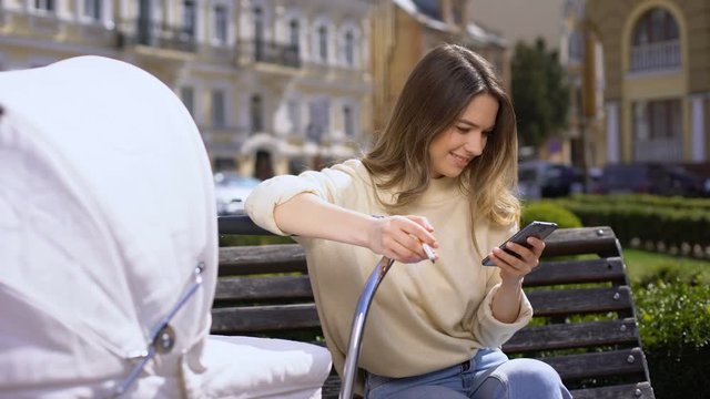 Irresponsible mother smoking and watching smartphone photos sitting carriage