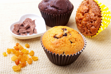 Assorted with Delicious homemade cupcakes with raisins and chocolate chips isolated on textile background. Muffins. Top view.