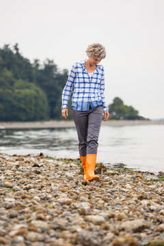 Beautiful, active, healthy middle aged mature woman enjoying exploring nature beachcombing on a rocky beach