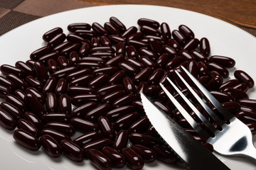 fork and knife with lots of capsules on a dish concept of over-relying on medicine
