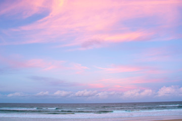 Naklejka na ściany i meble pretty pastel colour sky pink purple blue with fluffy cloud on beach with white sand Australia Gold Coast