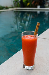 Fresh orange papaya juice in glass with bamboo tube on a  stone background near waterpool. Tropical Fruit. Top view. Free text space.