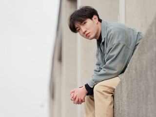 Portrait of a handsome Chinese young man sitting and looking at camera with blank expression, has...