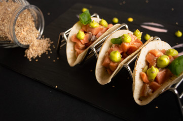 taquitos de tartar de salmon sobre un fondo negro