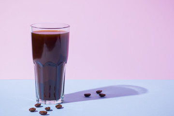 Coffee concept. Coffee drink and coffee beans on a pastel background. A glass of black coffee on a pink blue background. Pop art still life