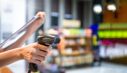 Close up barcode scanner in hand on blurred background,Inspection of goods in the warehouse,The concept of selling products in a supermarket,Spot focus,Copy space.