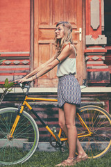 Obraz na płótnie Canvas Pretty woman sitting with old bicycle outdoors.