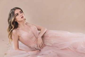 sensual woman in lace evening dress laying on the beige background