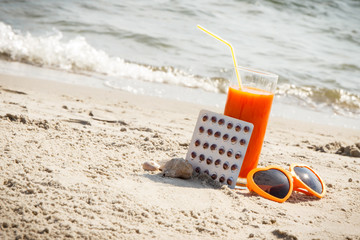 Medical pills, carrot juice and sunglasses on sand, vitamin A and beautiful, lasting tan