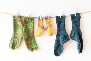 Colorful woolen socks on a rope on white background